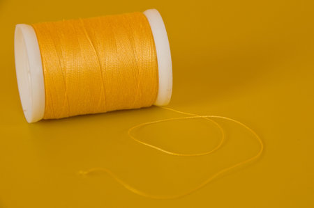 a reel of yellow sewing  thread on a yellow backgroundの写真素材