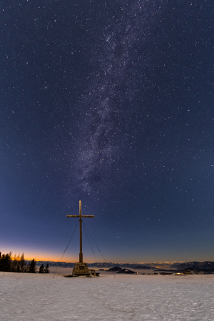 Milkyway over summit cross of snow covered mountain Schoeckl in Styria Austriaの写真素材