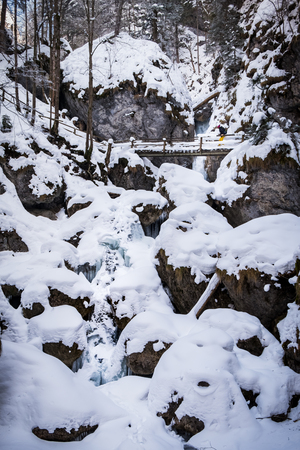Young women hiking over wooden ladders and bridges through snow covered gorge Baerenschuetzklamm with frozen icy waterfallsの写真素材