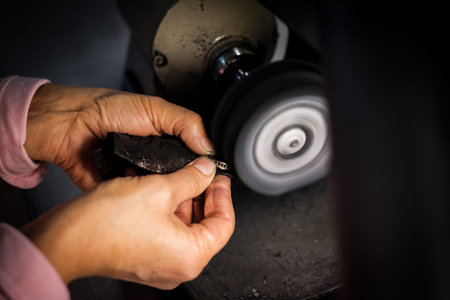 Jeweler polishes a gold ring on a bench grinder in an authentic jeweller's workshopの写真素材