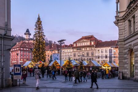 Christmas market Christkindlmarkt on main square with hill Schlossberg and landmark Uhrturm in Graz, Styria, Austriaのeditorial素材