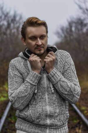 Cloudy autumn day. Railroad in fog. Portrait of young man.の写真素材