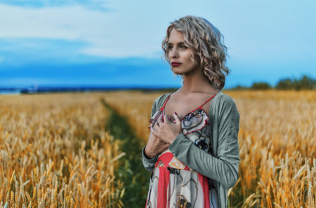Young beautiful woman looking into the distance. Wheat field in sunny summer day