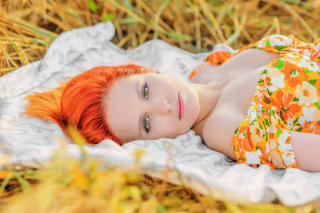 Beautiful young woman lying in field and looking into the camera. Summer dayの写真素材