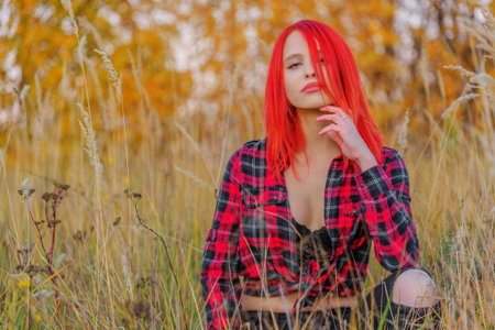 Beautiful young woman sitting on grass. Autumn day