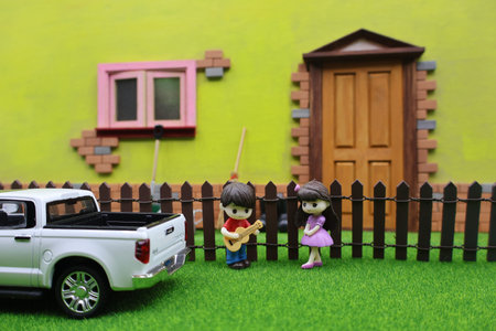 Miniature people on the green grass with house and car background.