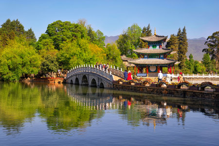 Lijiang, China - April 27, 2019: Tourists over the Suocui bridge with Moon Embracing Pavilion on the background. This scenic spot is in the Black Dragon Pool at the Jade Spring parkのeditorial素材