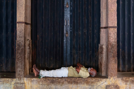 Srirangam, India - August 22, 2018: Middle aged man resting inside Sri Ranganathaswamy Temple. Is not uncommon in India to see pilgrim resting and sleeping inside hindu templesのeditorial素材