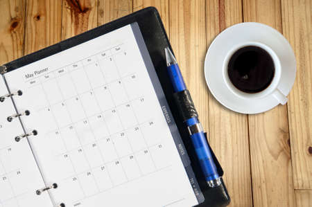 White cup of hot coffee and white sketch book on wood table の写真素材