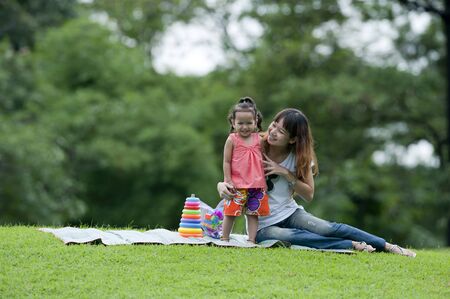 Little girl and her mother were playing toys in the garden. の写真素材