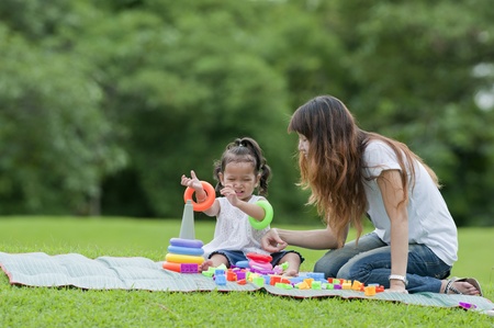 Little girl and her mother were playing toys in the garden. の写真素材