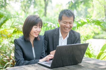 Woman sitting use computer on wooden table at home office ,background of green trees.