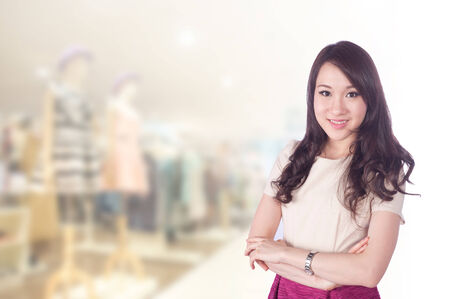 Asian businesswoman with long hair holding a sign board with a red hot sale has shopping mall .の写真素材