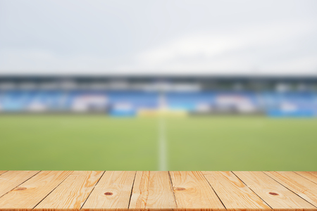 blurred soccer stadium in sunny day backgrounds with old vintage wooden desk tabletop,put and show your products on display or wallpaperの写真素材