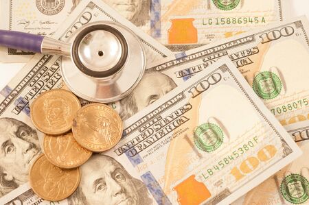 Stethoscope on a pile of money, depicting the health care industry conceptの写真素材