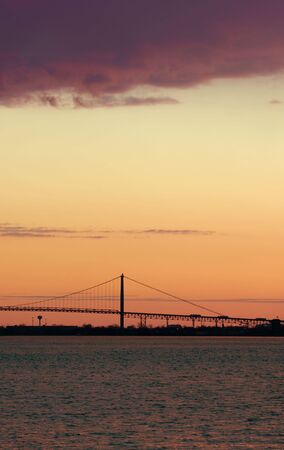 Trucks crossing a suspension bridge at sunsetの写真素材