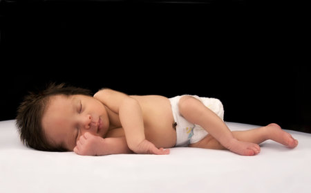 A smiling newborn infant sleeping on a white and black background