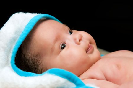 A cute baby with a towel on its head on a black background の写真素材