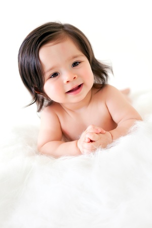 A pretty baby girl on a white fur skin with white backgroundの写真素材