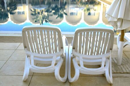 Two plank beds in the foreground against poolの写真素材
