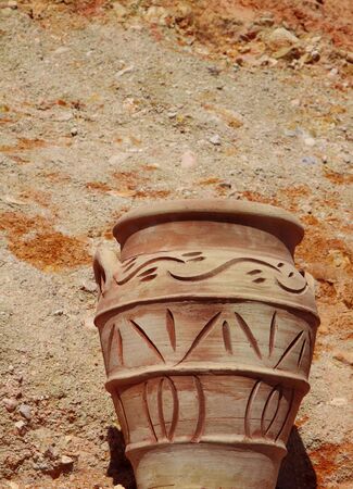 The clay jug shined with a shining sun against clay and sandの写真素材