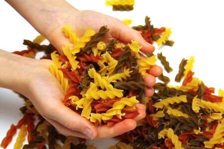 Coloured macaronis by a large plan in handsの写真素材