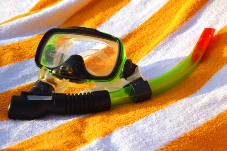 Mask and tube for a scuba diving, lying on a striped towelの写真素材