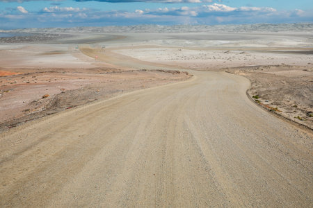 Gravel road in the middle of the desert, with blue skyの写真素材