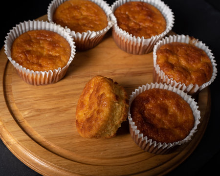 Golden sweet homemade and freshly baked cornbread muffins for lunch on wooden tray, close up.   Dark...