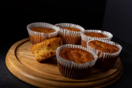 Golden sweet homemade and freshly baked cornbread muffins for lunch on wooden tray, close up.   Dark...