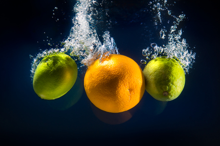 lime and orange splash in waterの写真素材