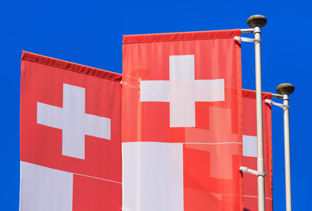 Flags of Switzerland against blue sky.