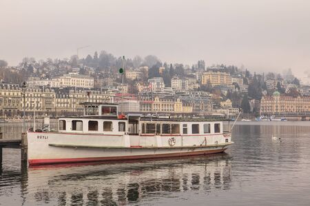 Lucerne, Switzerland - 3 December, 2013: view on the city and a boat at a pier on Lake Lucerne on a foggy winter day. Lucerne is a city in central Switzerland, it is the capital of the Canton of Lucerne and the capital of the district of the same name. Laのeditorial素材
