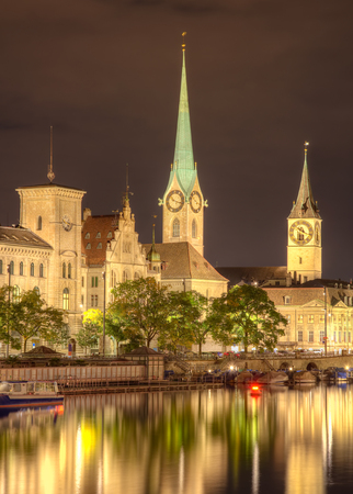 Historic buildings along the Limmat river, towers of the Fraumunster Cathedral and St. Peter Church in the city of Zurich, Switzerland at night. A HDR image with tone mapping applied.の写真素材