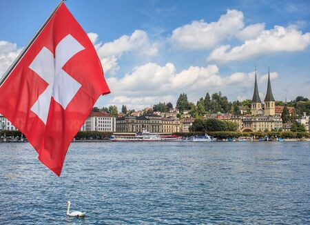 View in Lucerne, Switzerland in summertime: flag of Switzerland and Lake Lucerne with the city of Lucerne in the background.の写真素材
