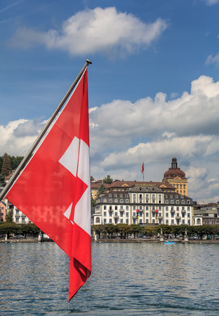 Lucerne, Switzerland - 14 August, 2009: flag of Switzerland, Lake Lucerne with the Hotel Schweizerhof building in the background. Lucerne is a city in central Switzerland, it is the capital of the Swiss Canton of Lucerne.のeditorial素材
