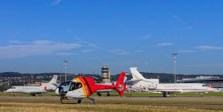 Kloten, Switzerland - 29 September, 2016: Eurocopter EC-120B Colibri helicopter and two Dassault Falcon 7X jets in the Zurich Airport. Zurich Airport, also known as Kloten Airport, is the largest international airport in Switzerland.のeditorial素材