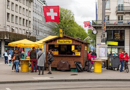 Zurich, Switzerland - 17 April, 2016: people at a kiosk serving raclette, temporarily installed on Paradeplatz square for the time of Sechselauten festivity. Sechselauten is a traditional spring holiday in the city of Zurich. Raclette is the name of a traのeditorial素材