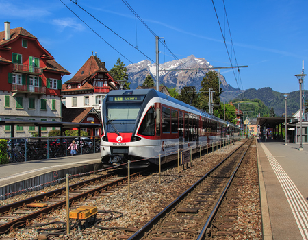 Stans, Switzerland - 8 May, 2016: the Stans railway station with a passenger train heading to the city of Lucerne at its platform, Mt. Pilatus in the background. The town of Stans is the capital of the Swiss canton of Nidwalden.のeditorial素材