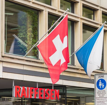 Zurich, Switzerland - 17 April, 2016: an office of the Raiffeisen bank decorated with flags of Switzerland and Zurich. Raiffeisen Switzerland is a Swiss cooperative bank headquartered in the city of St. Gallen, it is the third largest bank in Switzerland,のeditorial素材