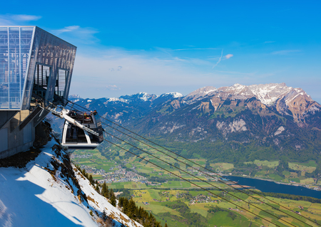 Mt. Stanserhorn, Switzerland - May 7, 2016: people in a gondola of the Stanserhorn Cabrio overhead cable car heading downwards from the station on the top of the mountain, summit of Mt. Pilatus on the right side of the image. The Stanserhorn Cabrio is theのeditorial素材