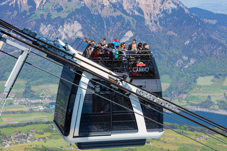 Mt. Stanserhorn, Switzerland - May 7, 2016: people in a gondola of the Stanserhorn Cabrio overhead cable car at the station on the top of the mountain. The Stanserhorn Cabrio is the world's first double deck open top overhead cable car, it carries 60 passのeditorial素材