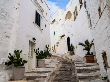 Ancient cobblestone alley with traditional white houses in Ostuni, Apulia region, southern Italyの写真素材