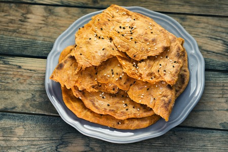 Tortillas, tomato with sesame seeds on a blue plate on a wooden background.の写真素材
