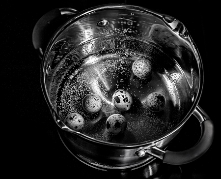 Quail eggs boil in a metal saucepan. Black and white picture.の写真素材