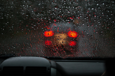View from a rain-drenched windshield on blurred back lights of a car in front. Heavy rainの写真素材