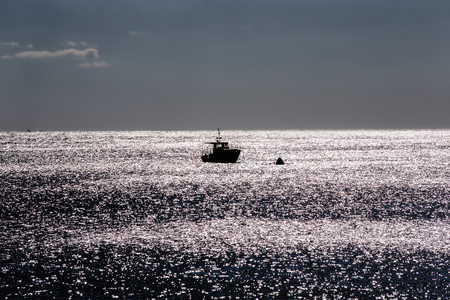 A lonely ship in the sea near a buoy at dusk. Open sea and skyline.の写真素材
