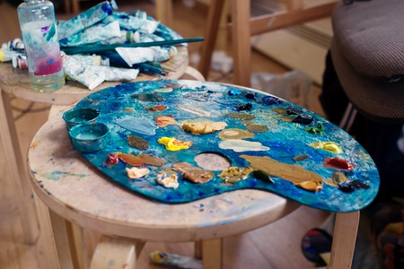 Color palette of the artist is on the table in the art studio. Around are scattered tubes of paintの写真素材