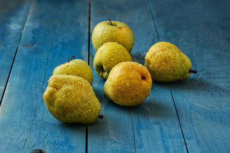 Fresh wet apples and pears with water drops on the dark blue wooden background.の写真素材