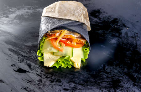 Black roll with cheese, salad, chicken and vegetablesの写真素材